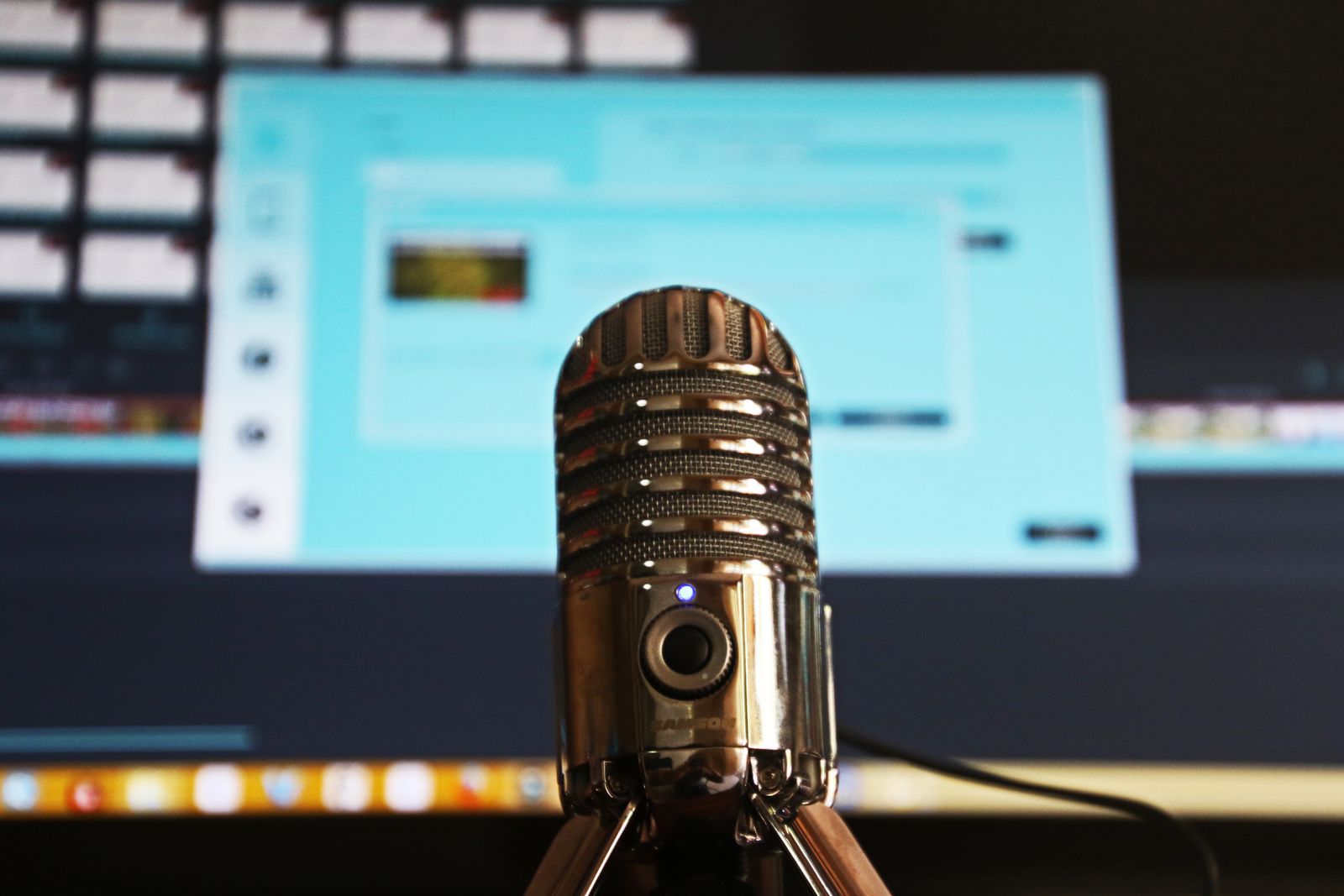 Microfone condensador em pedestal diante de monitor com software de áudio aberto