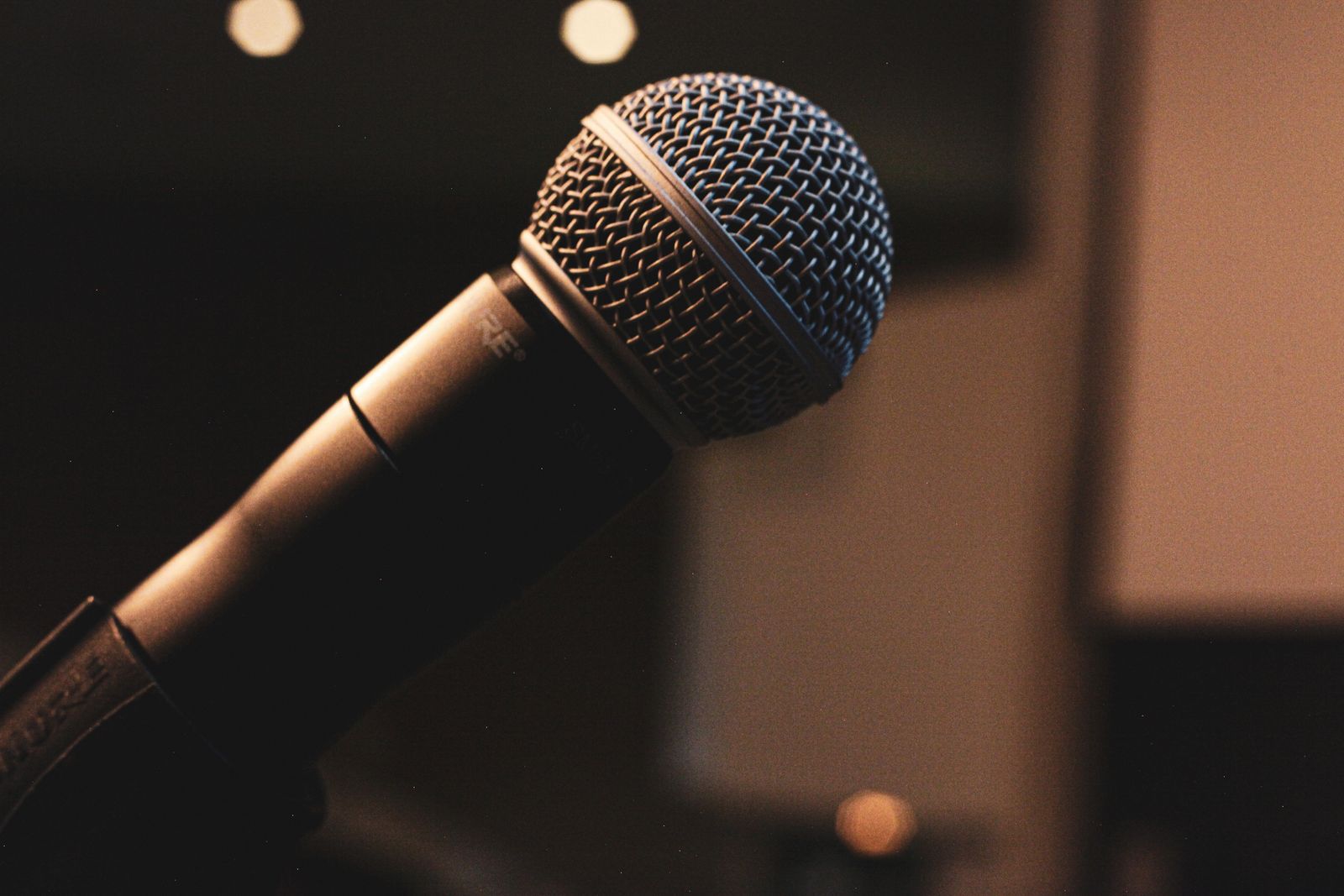 Microfone dinâmico de mão em close, montado em pedestal de palco